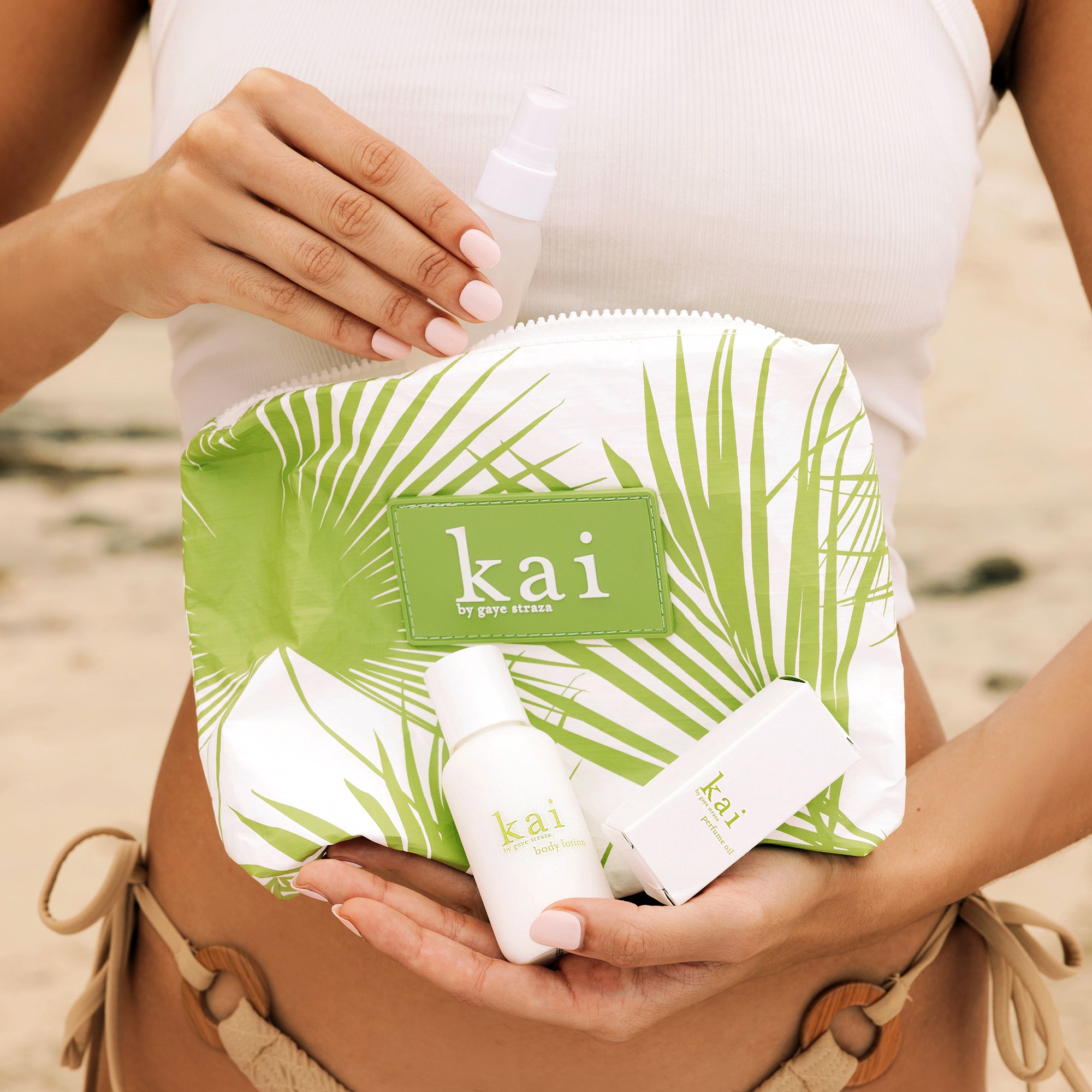 kai & aloha cosmetic bag with products on a beach